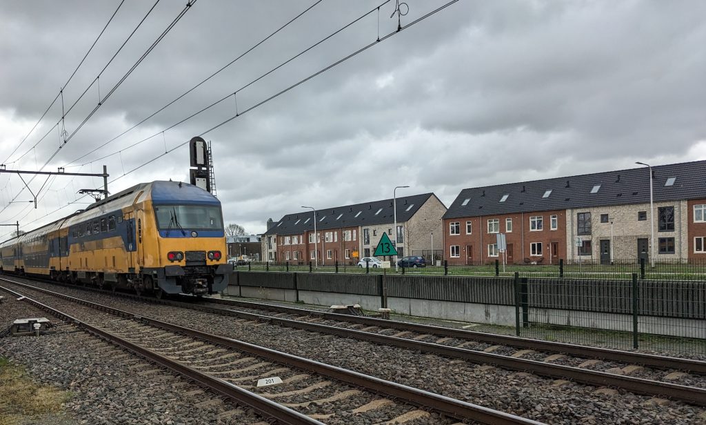 Trein rijdt langs woonwijk